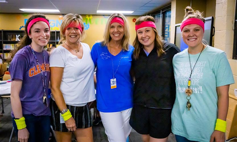 Teachers pose while wearing neon sweatbands